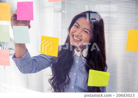 Asian businesswoman using sticky notes on wall 20683023