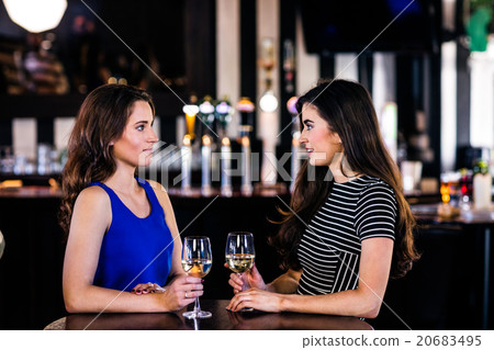 Brunettes talking and holding glasses of white wine 20683495