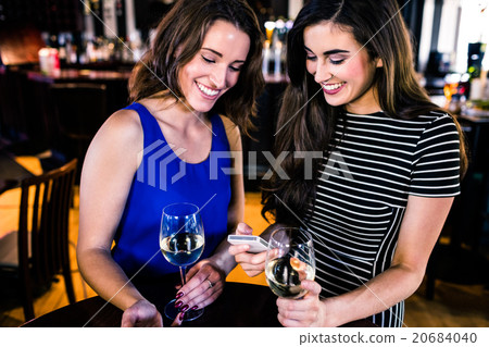 Friends texting and having a glass of wine Friends texting and having a glass of wine 20684040
