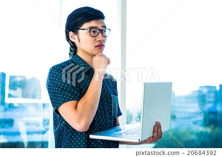 Thoughtful hipster using his laptop Thoughtful hipster using his laptop 20684392