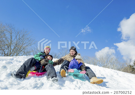 4 people family playing sledding on a snow hill 20700252