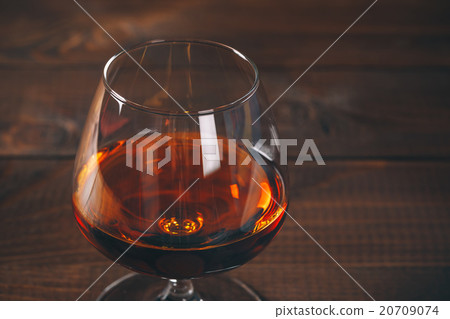 Glass of cognac on the wooden table. 20709074