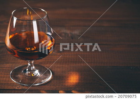 Glass of cognac on the wooden table. 20709075