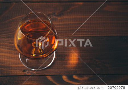 Glass of cognac on the wooden table. 20709076