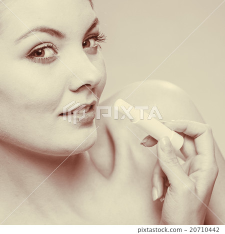 Young woman take balm on lips. 20710442
