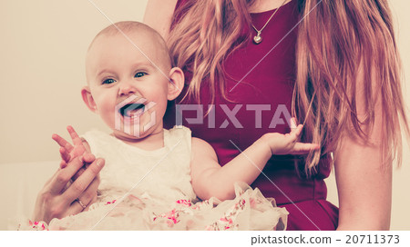 Happy baby girl on mother knees. 20711373