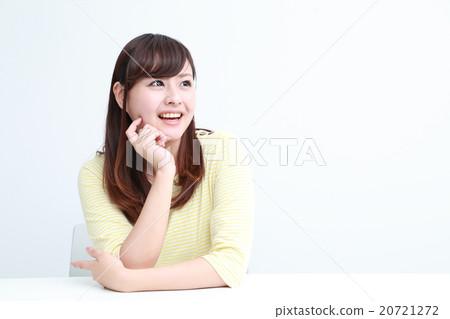 一個女人在她二十多歲坐在辦公桌前帶著微笑 一個女人在她二十多歲坐在辦公桌前帶著微笑 20721272