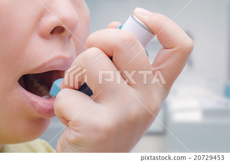Woman uses an inhaler during an asthma attack 20729453