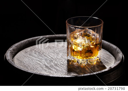 Glass of whiskey with ice on wooden barrel 20731798