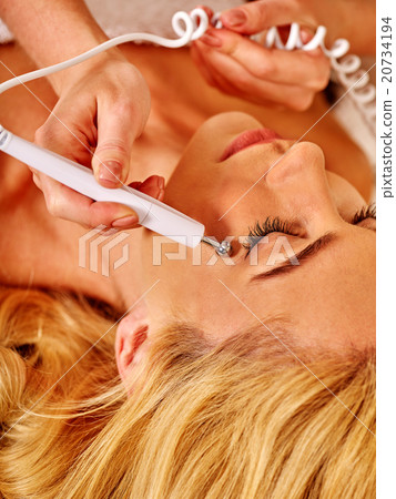 Young woman receiving electric facial massage. Young woman receiving electric facial massage. 20734194