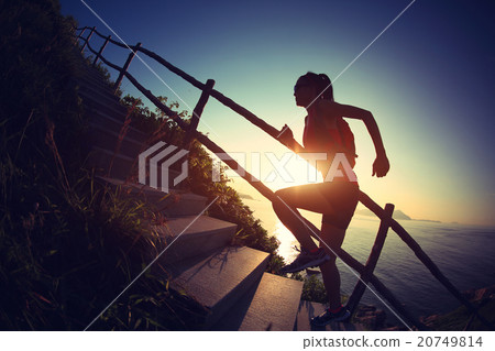 woman trail runner on seaside mountain stairs 20749814
