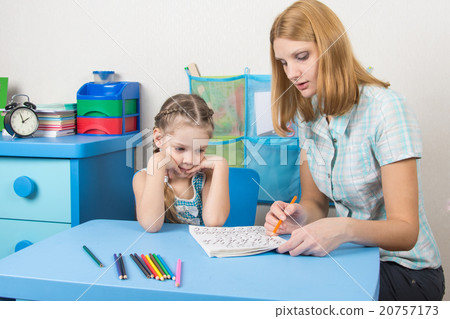 Five-year girl with interest looks at the teaching material explained by an adult Five-year girl with interest looks at the teaching material explained by an adult 20757173