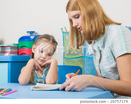Five-year girl with interest looking notebook and listening to the explanation of the teacher 20757174