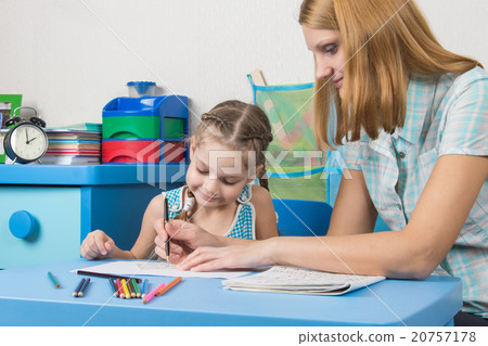 A teacher helps a five-year girl with a ruler to draw A teacher helps a five-year girl with a ruler to draw 20757178