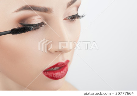 Attractive girl is putting on make-up 20777664
