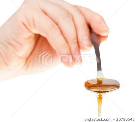 hand holds metal spoon with clear honey 20786545
