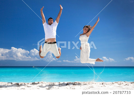 Happy newlyweds jumping up on beach 20787733
