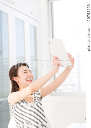 觀看一種片劑的婦女在屋子裡 觀看一種片劑的婦女在屋子裡 20792200