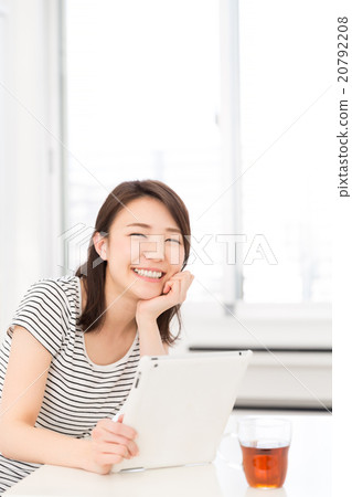觀看一種片劑的婦女在屋子裡 觀看一種片劑的婦女在屋子裡 20792208