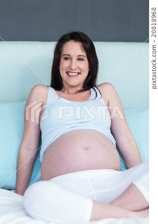 Pregnant woman sitting on bed Pregnant woman sitting on bed 20818968