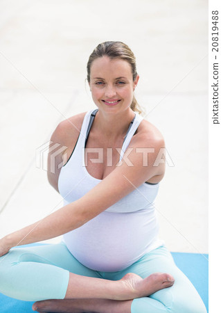 Pregnant woman stretching on mat 20819488