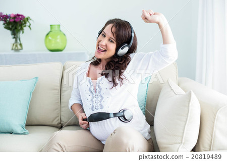 Pregnant woman holding headphone on belly 20819489