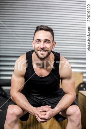 Fit man sitting on wooden box Fit man sitting on wooden box 20819490