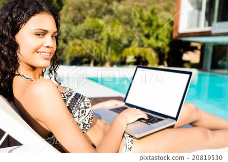 Fit brunette lying on deck chair and using laptop 20819530