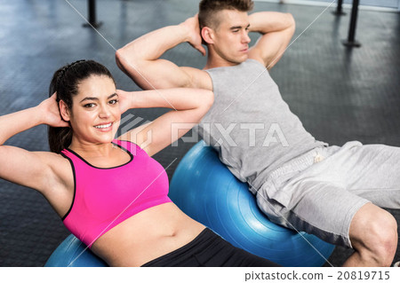 Fit couple doing abdominal crunches on fitness ball Fit couple doing abdominal crunches on fitness ball 20819715