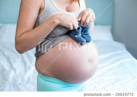Pregnant woman with knitted slippers on her belly Pregnant woman with knitted slippers on her belly 20819772