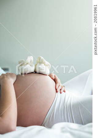 Pregnant woman with baby shoes on belly Pregnant woman with baby shoes on belly 20819961