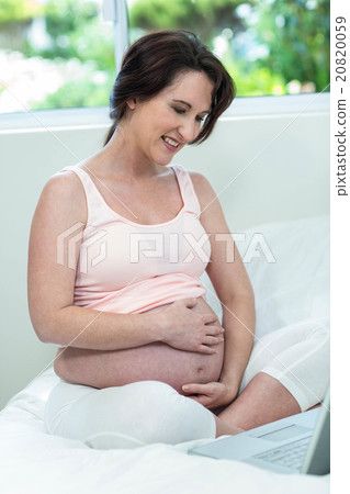 Pregnant woman relaxing with her laptop 20820059