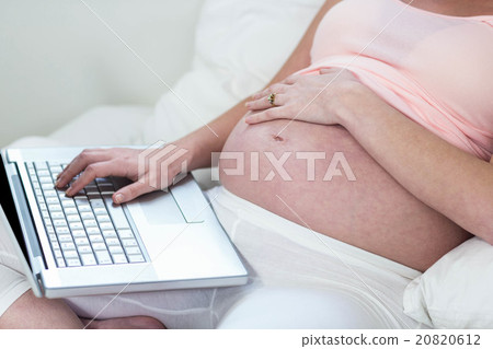 Pregnant woman relaxing with her laptop 20820612