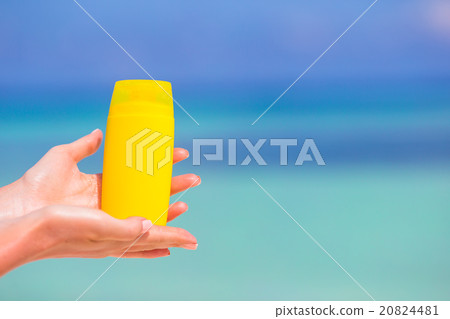 Female hands with suncream bottle background blue 20824481