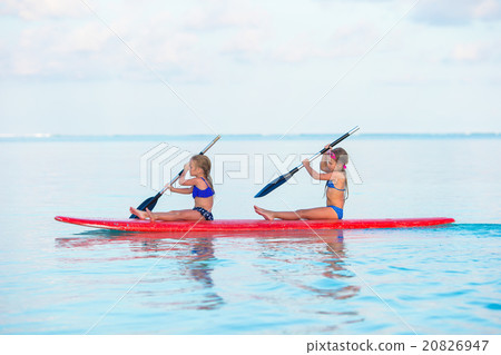 Little girls swimming on surfboard during summer 20826947