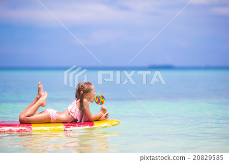 Little girl with lollipop have fun on surfboard in Little girl with lollipop have fun on surfboard in 20829585