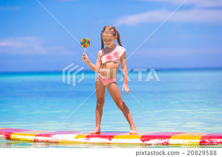 Little girl with lollipop have fun on surfboard in Little girl with lollipop have fun on surfboard in 20829588