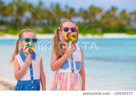Two little girls eating bright lollipops on the Two little girls eating bright lollipops on the 20830577
