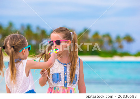 Two little girls eating bright lollipops on the Two little girls eating bright lollipops on the 20830588