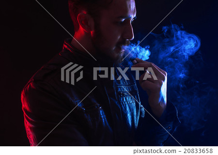 well-dressed bearded man smoking electronic cigarette in studio 20833658