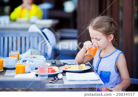 Adorable little girl have breakfast drinking juice Adorable little girl have breakfast drinking juice 20834557