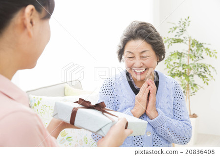 A young woman giving a gift to a senior woman A young woman giving a gift to a senior woman 20836408
