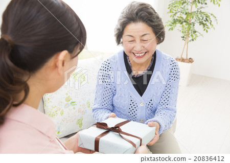 A young woman giving a gift to a senior woman A young woman giving a gift to a senior woman 20836412