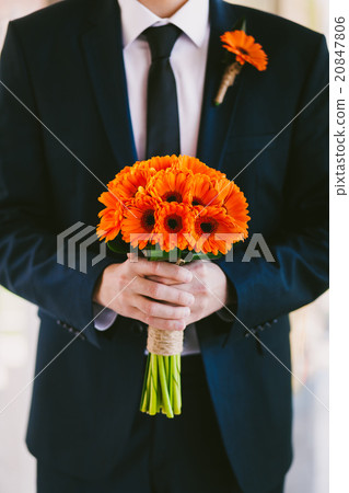 Groom in blue suit holding wedding bouquet of flowers in hands 20847806
