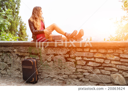 Girl in the sun on a wall with suitcase waiting. Girl in the sun on a wall with suitcase waiting. 20863624