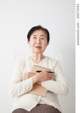 A senior woman recollecting his own history holding notes, thinking 20872083