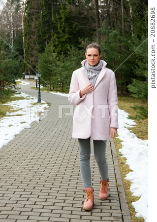 Pretty girl in pink coat walking along pathway in forest 20882698