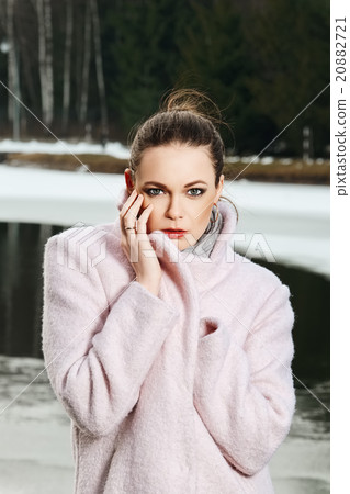 Pretty girl in pink coat near lake in winter forest Pretty girl in pink coat near lake in winter forest 20882721