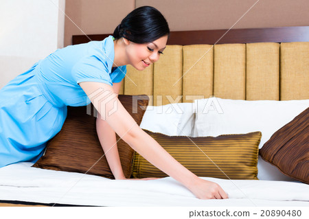 Chambermaid making bed in Asian hotel room 20890480