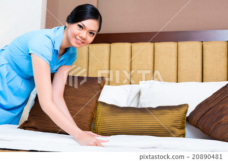 Chambermaid making bed in Asian hotel room 20890481